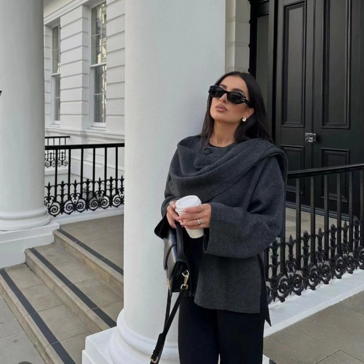 Stylish woman posing in oversized dark grey wool jacket near columns