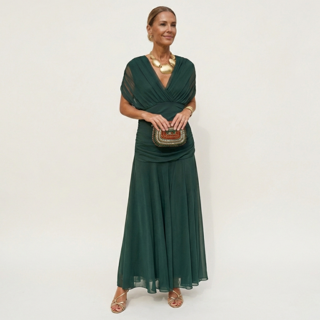 Woman wearing a dark green flowing V-neck maxi dress with gold accessories