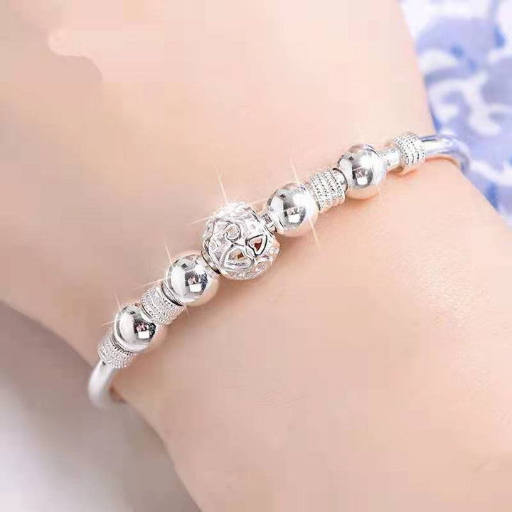 Close-up shot of silver charm bracelet worn on wrist showcasing detailed beads