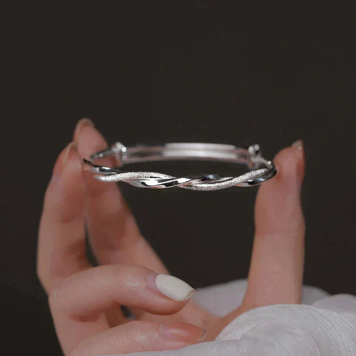 Fingers holding the handcrafted silver spiral bangle