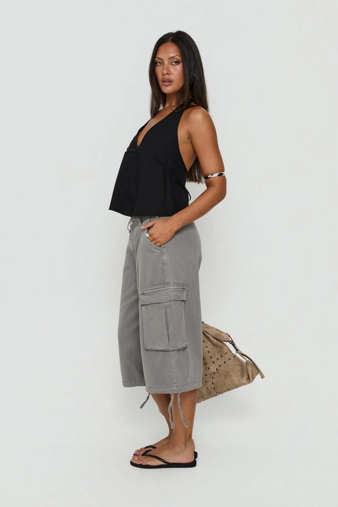 Side view of model wearing grey cargo utility shorts with a black halter top