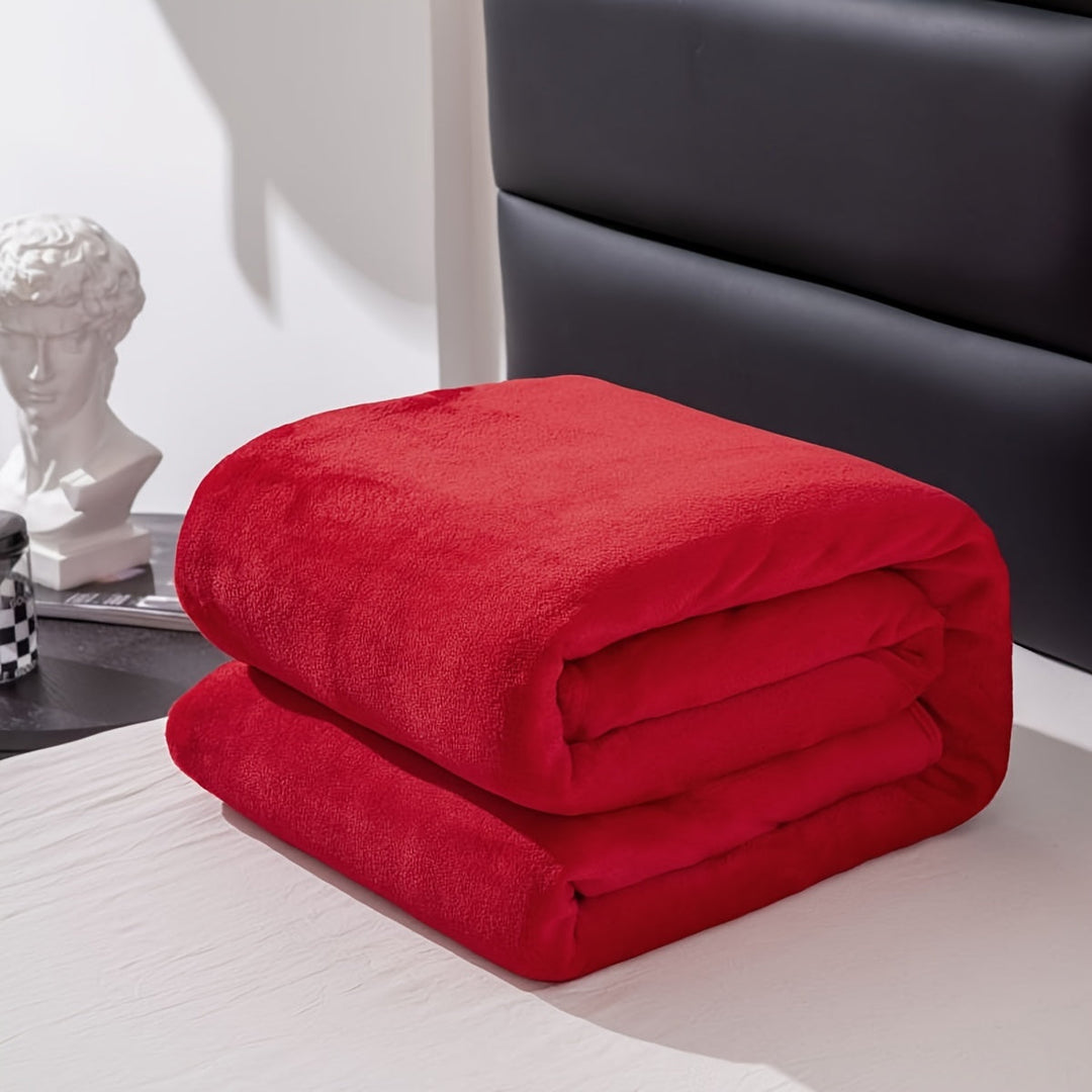 Folded bright red flannel blanket displayed on a bed setup