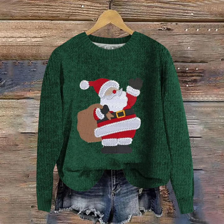 Green women's Christmas sweater featuring a cheerful Santa graphic hanging against a wooden background