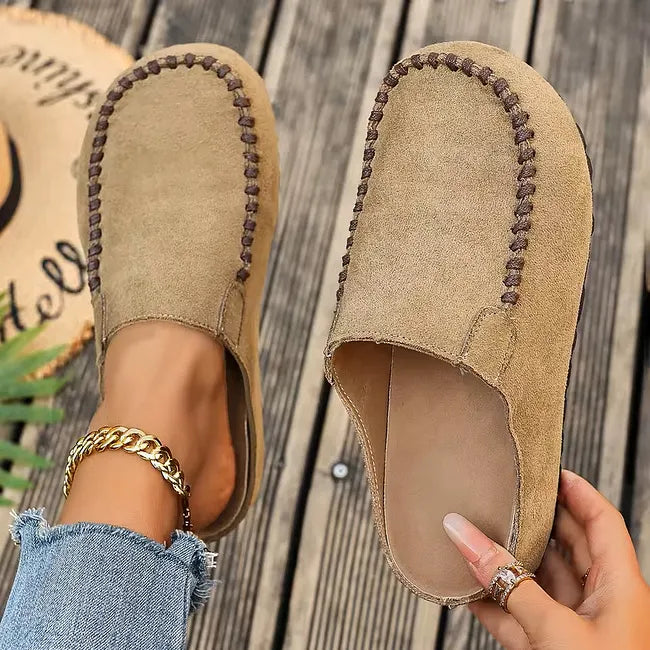 Close-up of brown slip-on sandals featuring decorative contrast stitching