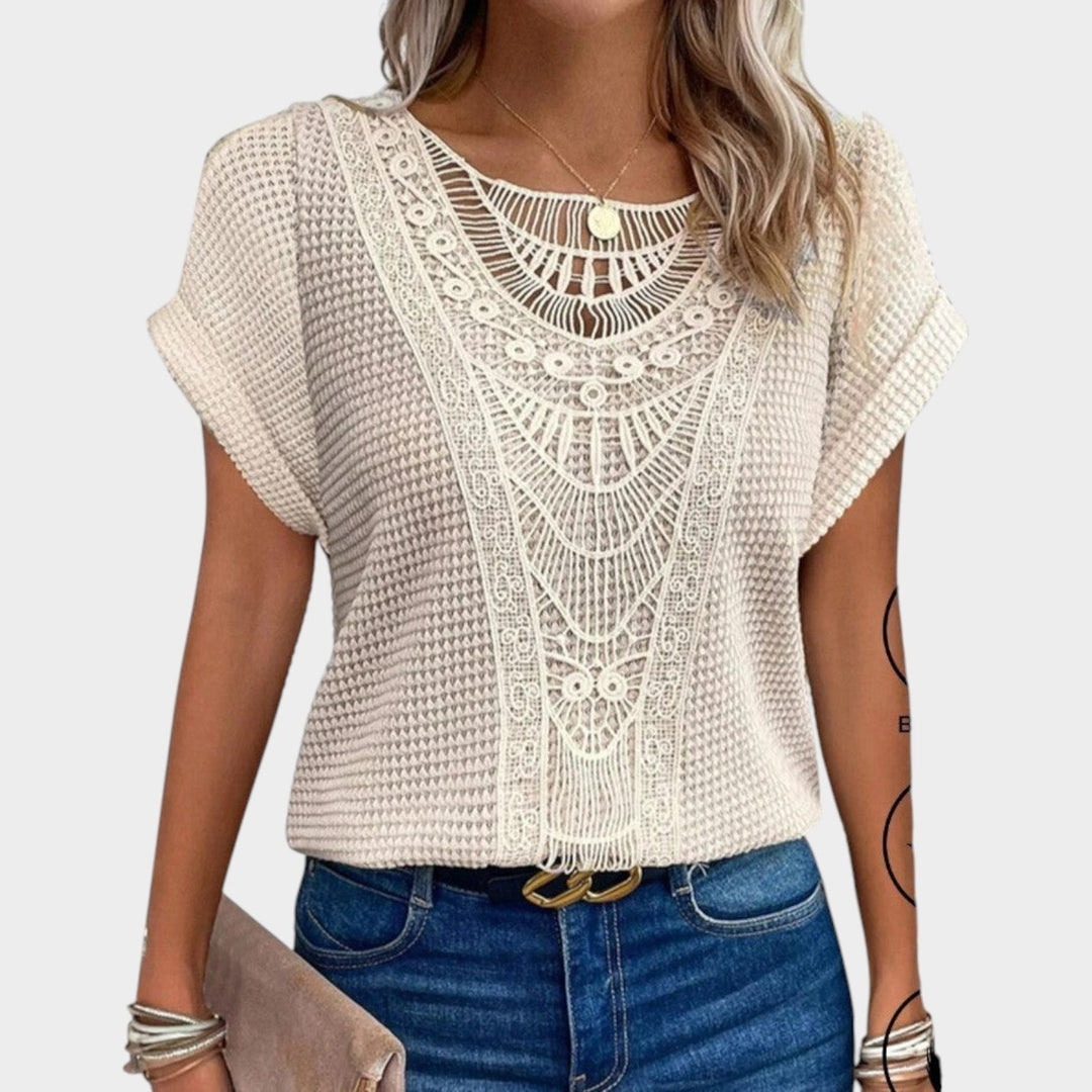 Woman wearing an apricot short sleeve lace blouse paired with jeans
