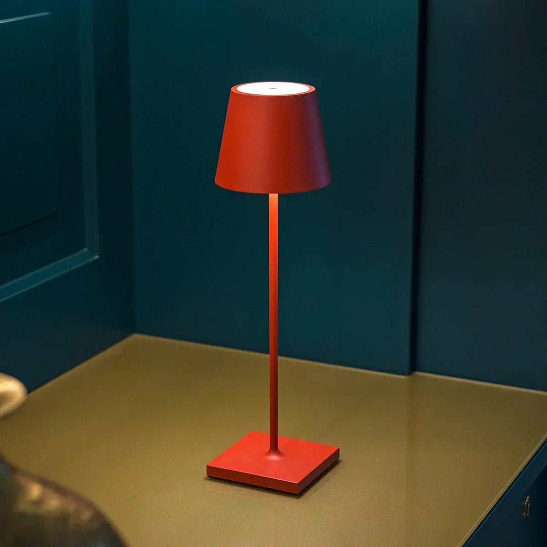 Matte Red wireless LED table lamp casting warm light against a dark accent wall