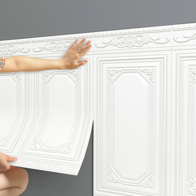 Person installing white 3D peel-and-stick wall panels on an interior wall