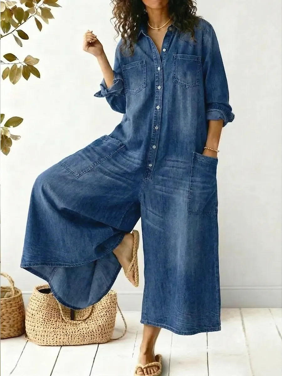 Woman wearing blue wide-leg button-front jumpsuit posing with one leg raised