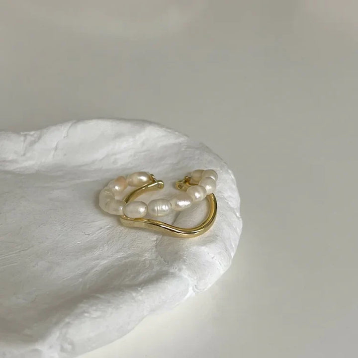 Double-layered gold pearl ring resting on a white ceramic dish