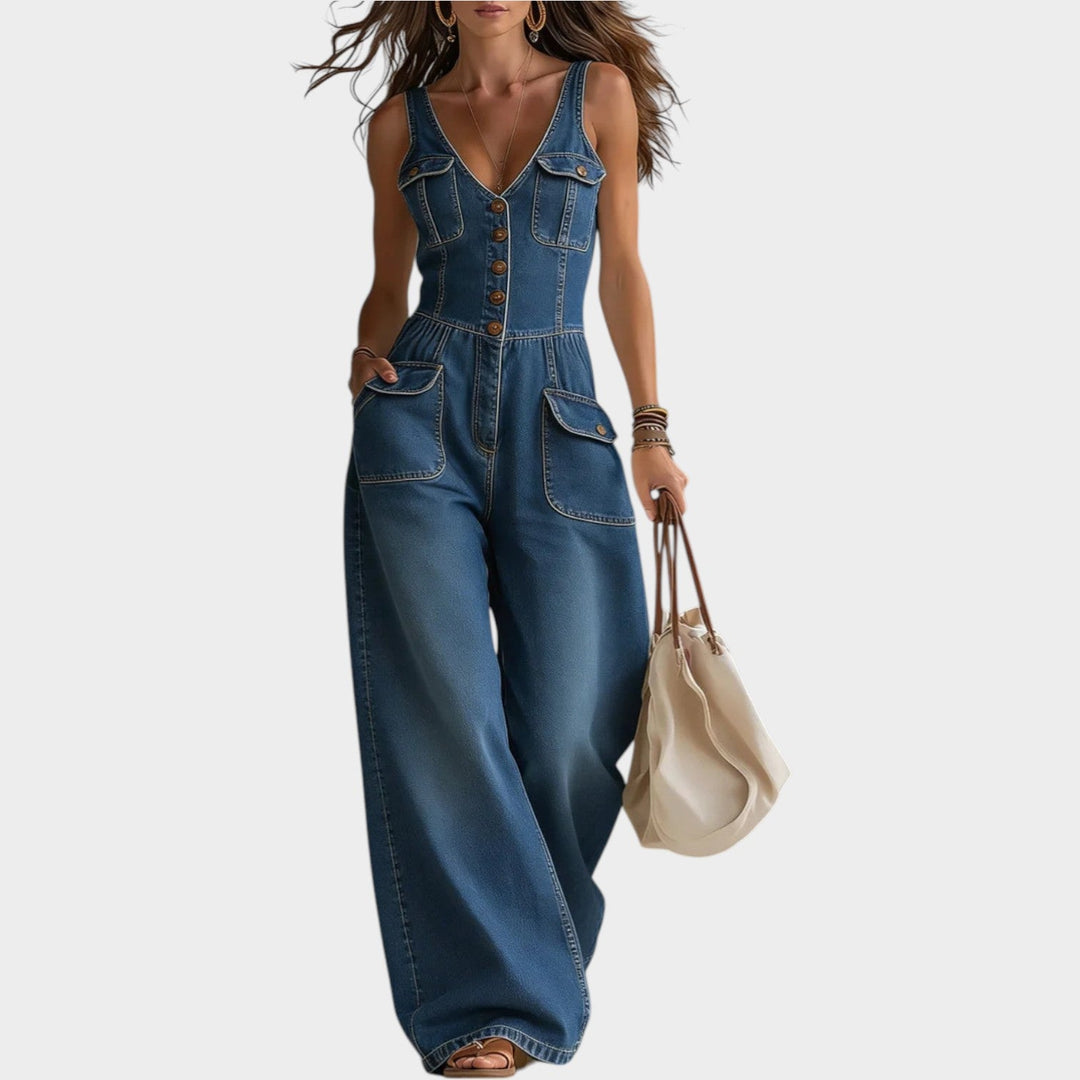 Model wearing navy denim wide leg button-up jumpsuit with utility pockets