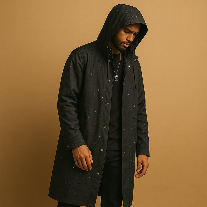 Man wearing black waterproof hooded long rain jacket with water droplets detail