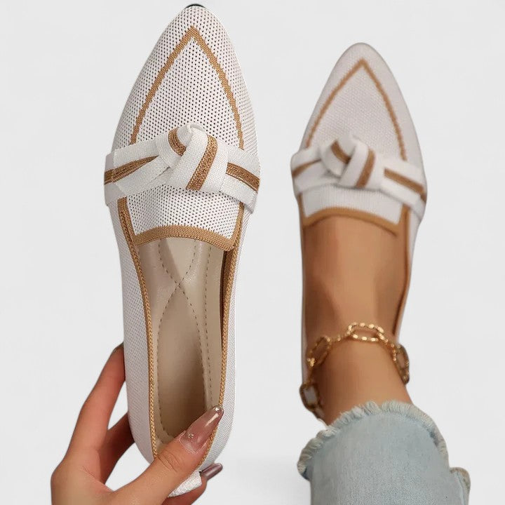 White pointed-toe knot loafers with contrasting trim displayed closely