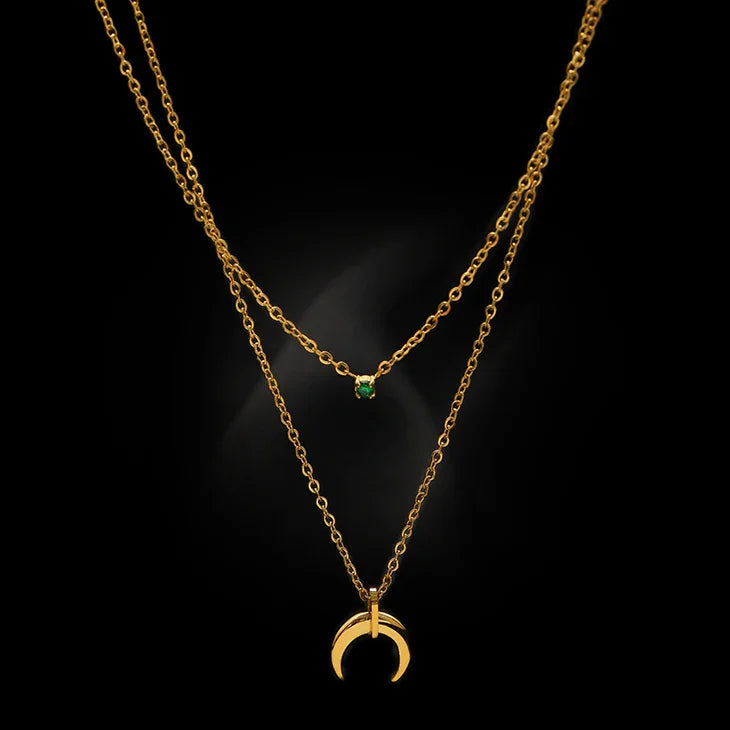Close-up of double crescent moon necklace with green stone on black background