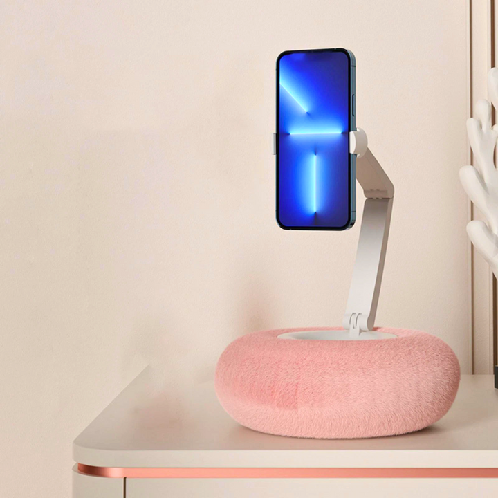 Pink adjustable mobile phone holder pillow holding a smartphone vertically on a desk