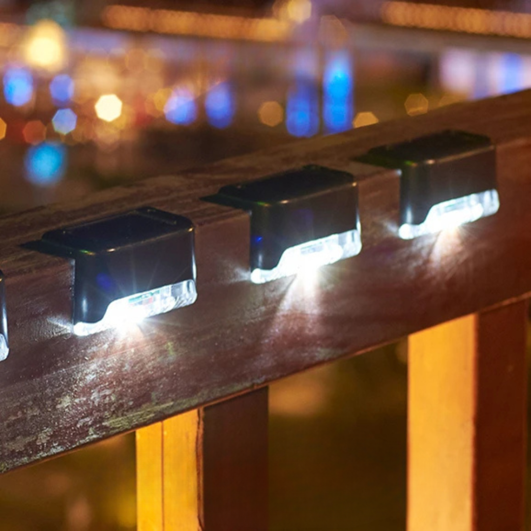 Solar powered step lights illuminating a wooden deck railing at night