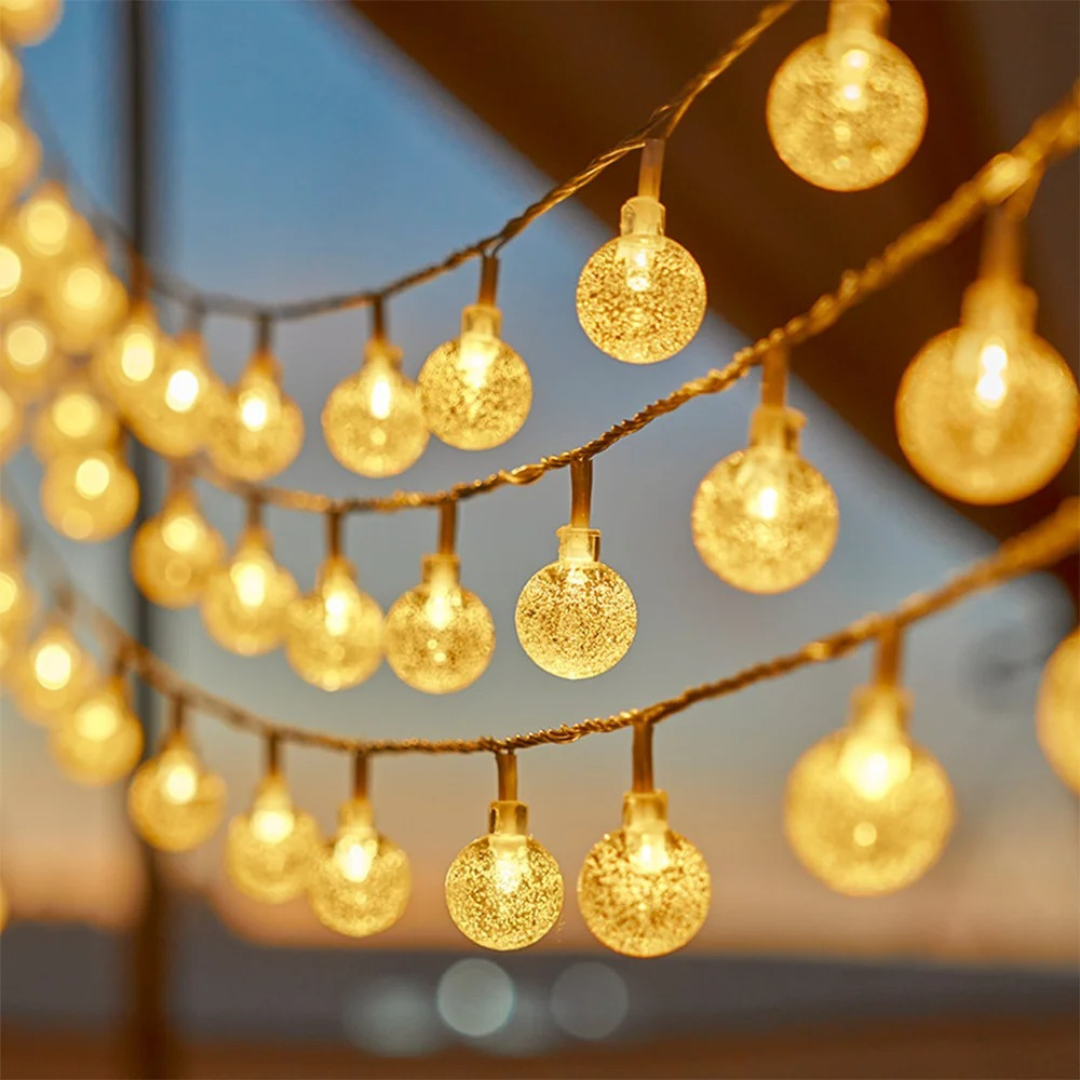 Warm white LED globe string lights glowing outdoors at dusk