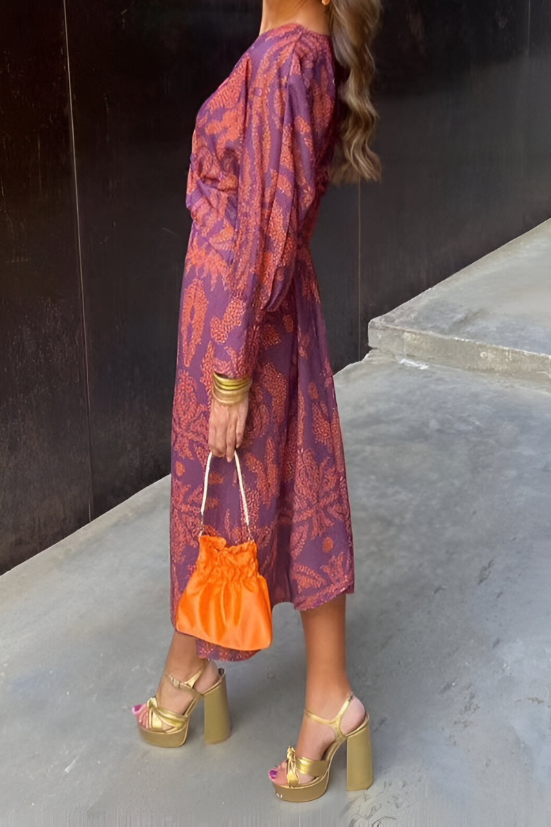 Woman wearing purple floral midi dress holding orange handbag