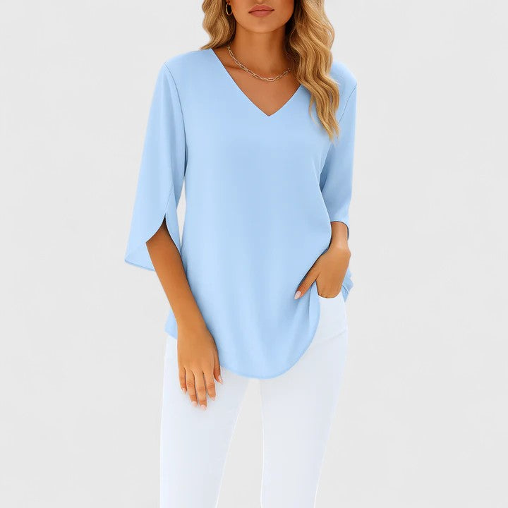 Woman wearing light blue V-neck split-sleeve summer blouse with white pants