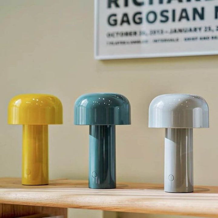 Yellow, blue, and grey mushroom lamps sitting on a wooden shelf indoors