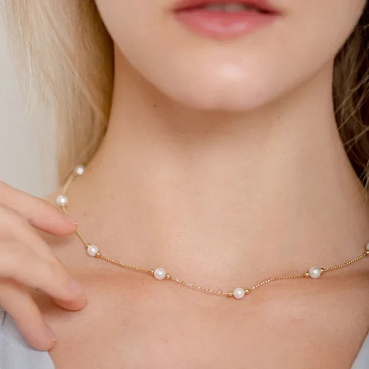 Close-up detail of the gold chain and pearls worn by a model