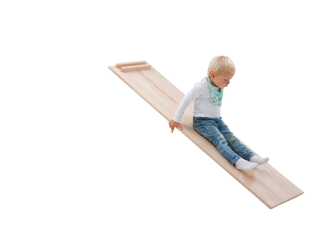Child sitting on the wooden reversible ladder and slide board