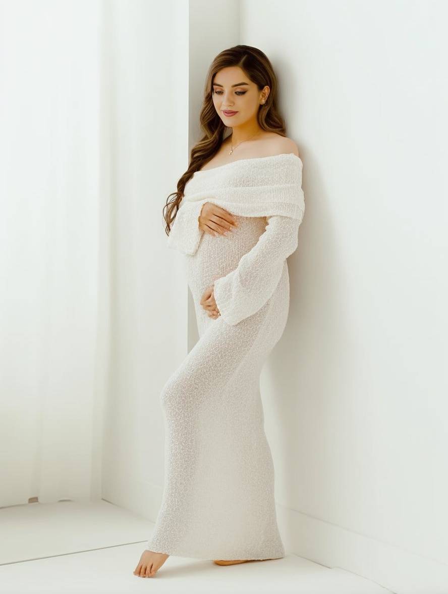 Full-length side profile of a pregnant woman wearing an elegant white knit maternity dress