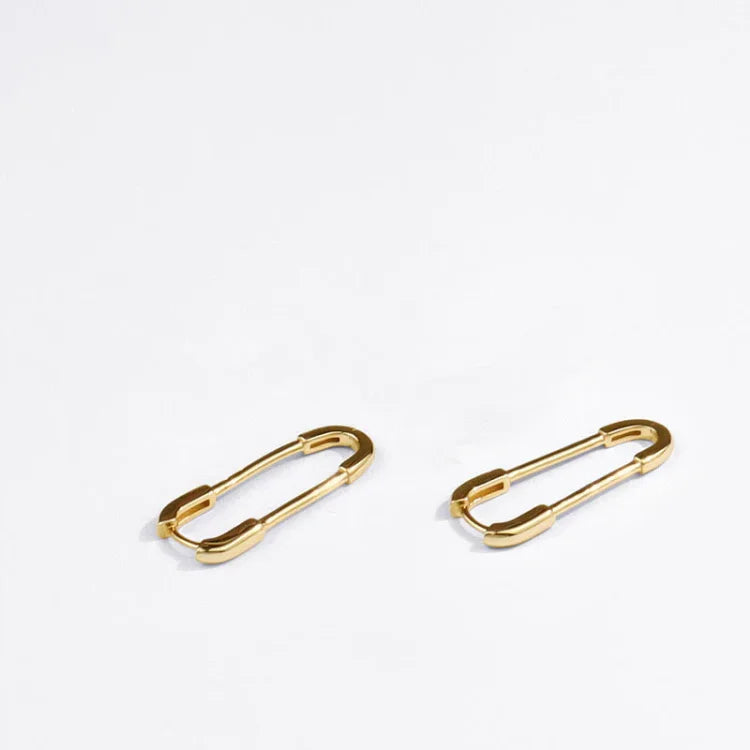 Gold geometric paperclip drop earrings displayed on a white surface