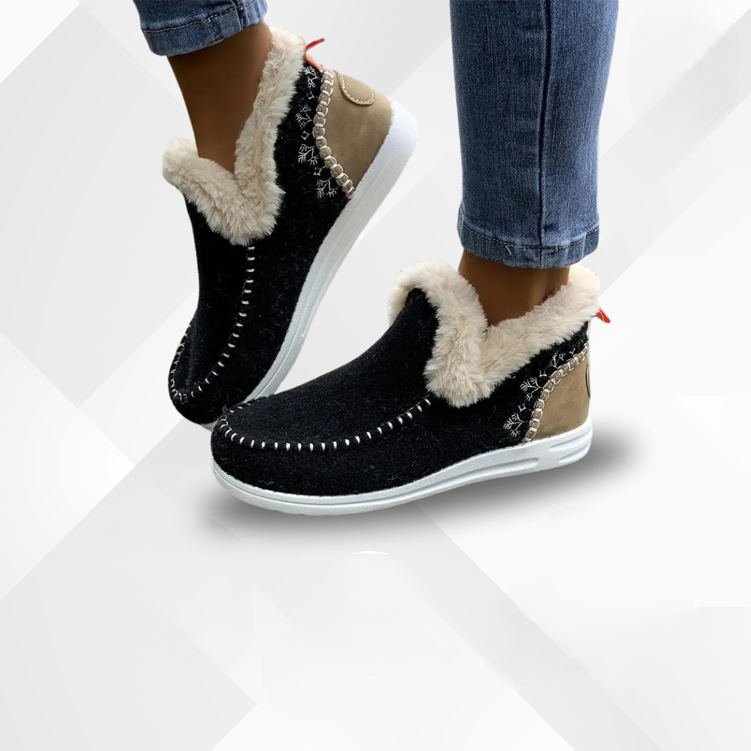Women's black slippers with plush lining and decorative stitching worn with jeans