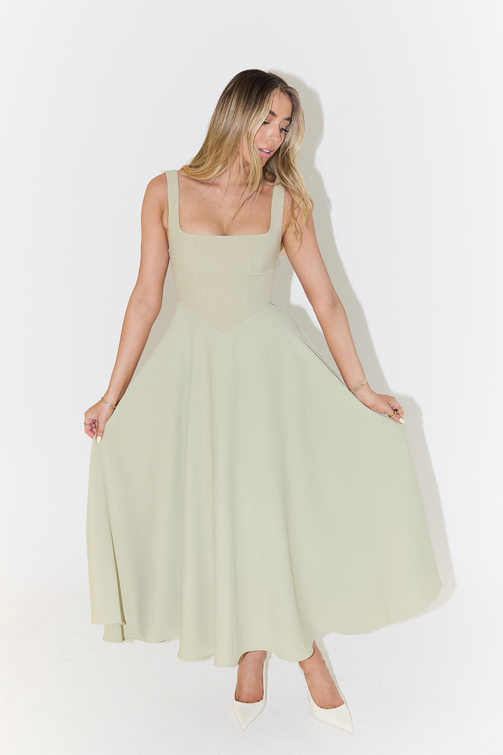 Model posing in a sage green square neck midi dress