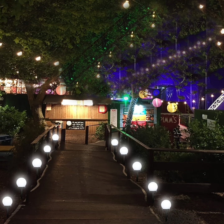 Water-resistant spherical outdoor lamp glowing brightly beside a garden path.