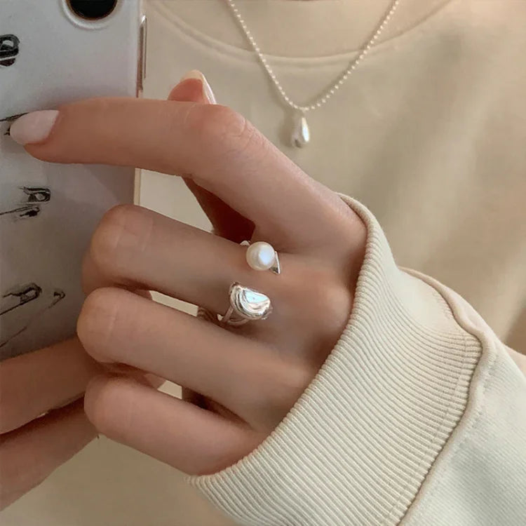 Hand wearing the elegant pearl bean ring next to a smartphone.