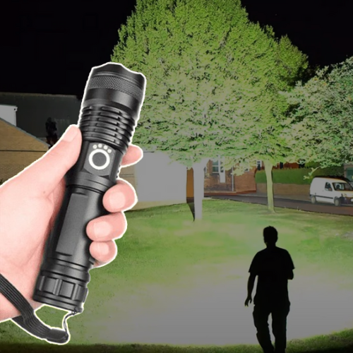Hand holding high-lumen tactical LED flashlight illuminating a dark park at night
