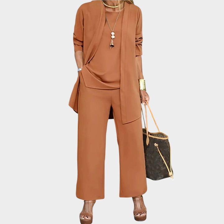 A model wearing a caramel women's three-piece cardigan, top, and wide-leg trousers set with a handbag.
