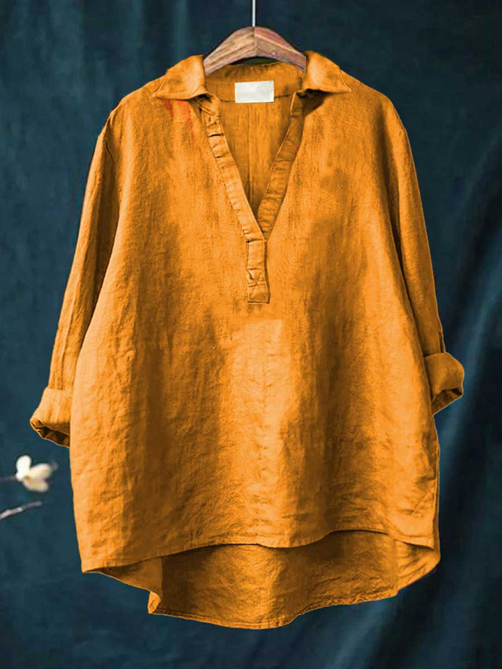 Yellow women's long sleeve blouse hanging against dark background