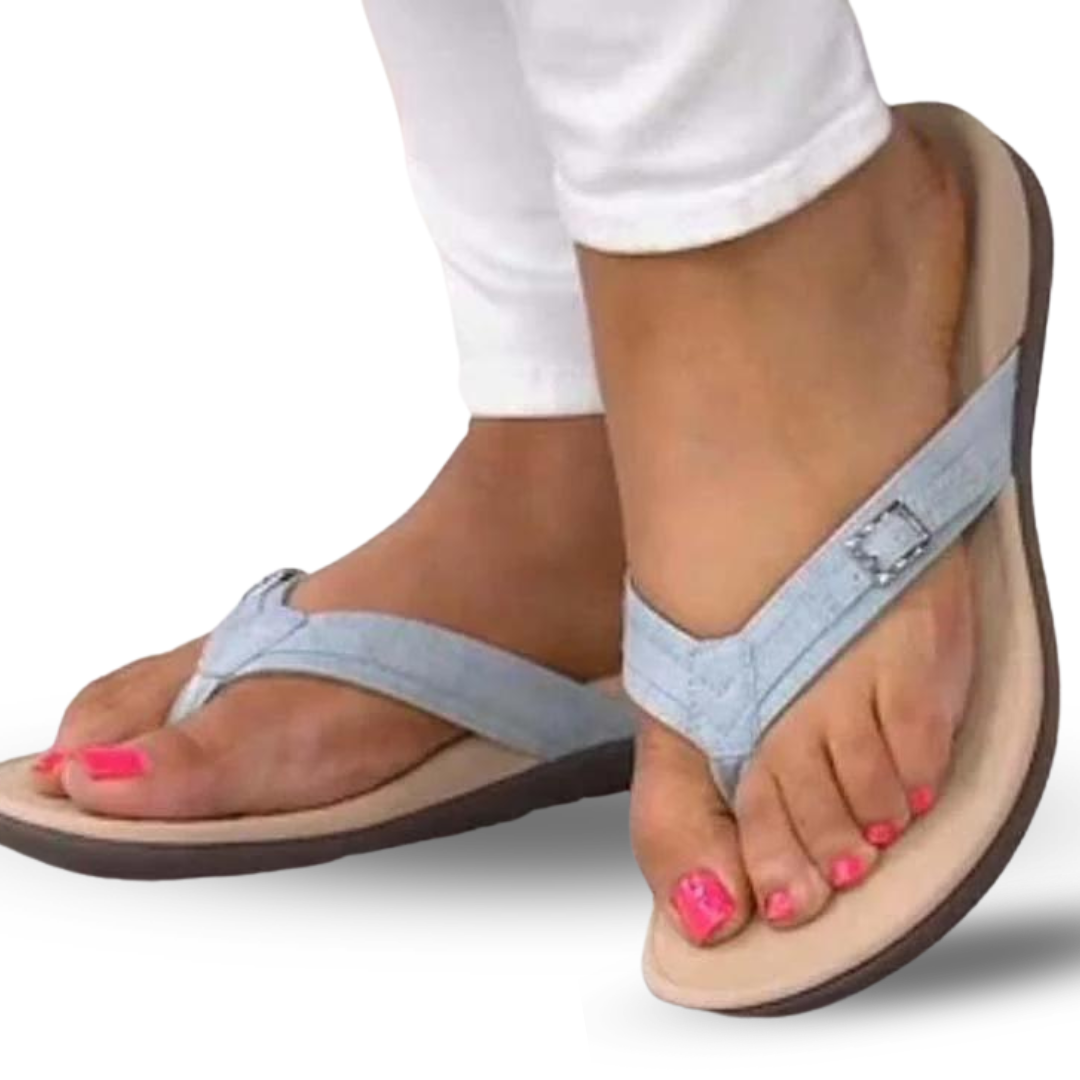 Close-up of a woman wearing light blue orthopedic support sandals with white trousers