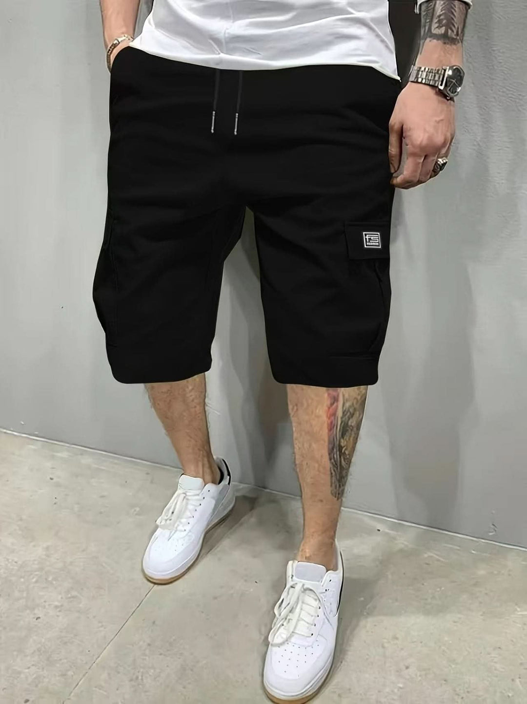 Man wearing black modern relaxed style utility shorts with white sneakers