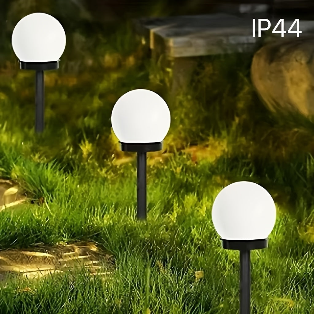 Outdoor view of spherical solar garden lights illuminating a grassy lawn at dusk