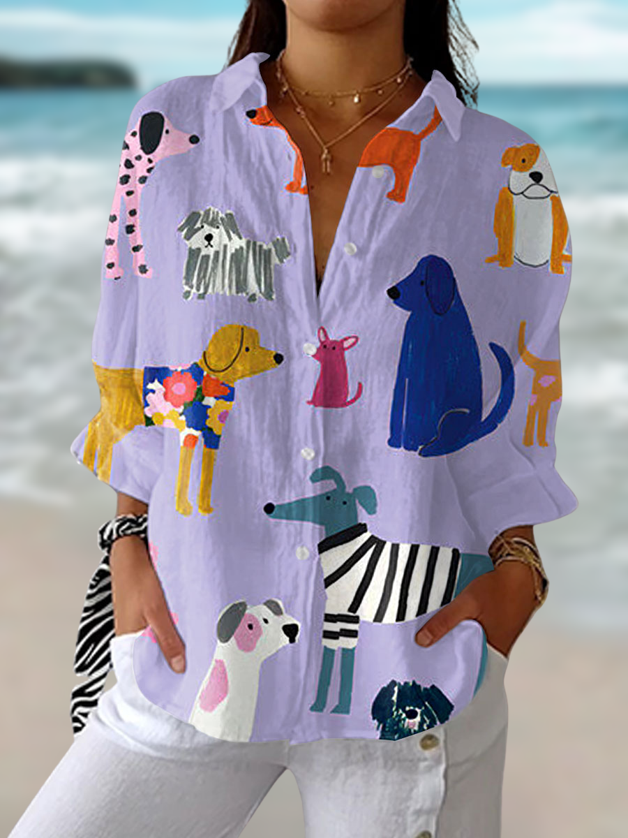 Woman wearing a purple button-down blouse with a playful multi-colored dog print against a beach background.