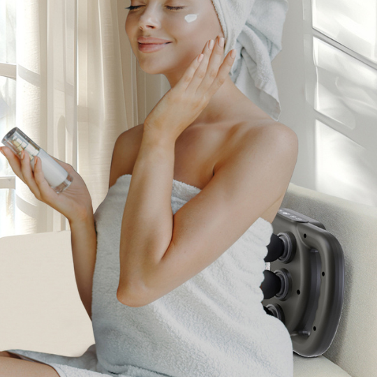 Woman relaxing on a couch using the six-head massage gun on her back