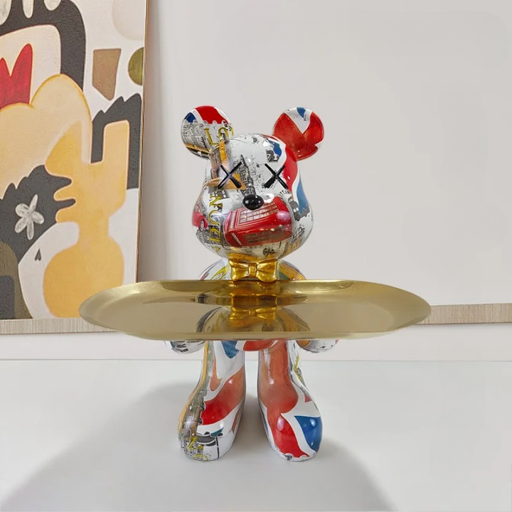 Multi-colored graphic patterned bear storage sculpture with golden tray against a neutral background.