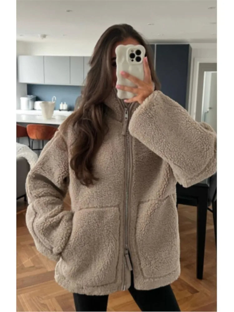 Woman wearing a beige teddy fleece jacket in a modern kitchen