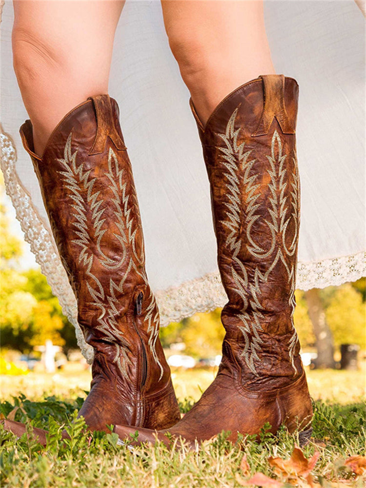 Brown knee-high cowboy boots with vintage embroidery worn outdoors