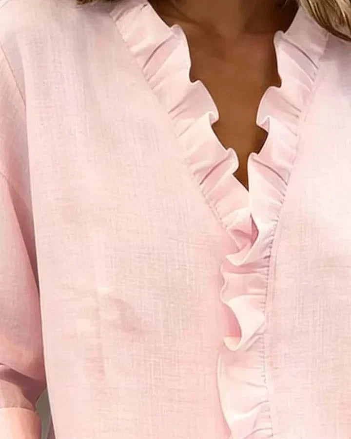 Full view of elegant ruffled blouse hanging on display
