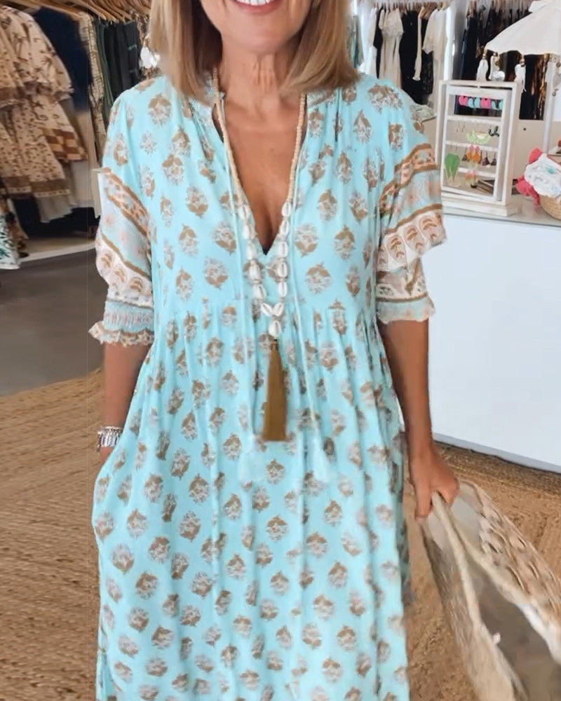 Close-up of model wearing blue Verona printed V-neck dress with statement necklace