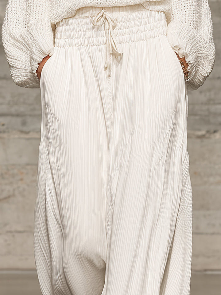 Detailed shot focusing on the textured fabric and pockets of the white wide-leg trousers.
