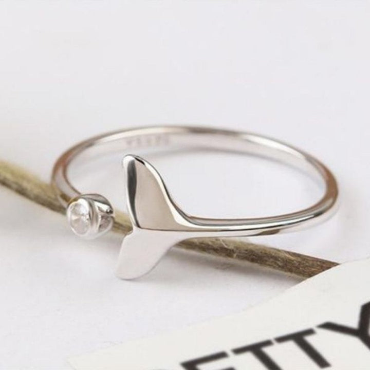 Close-up of silver dolphin tail ring showing polished metal and crystal detail