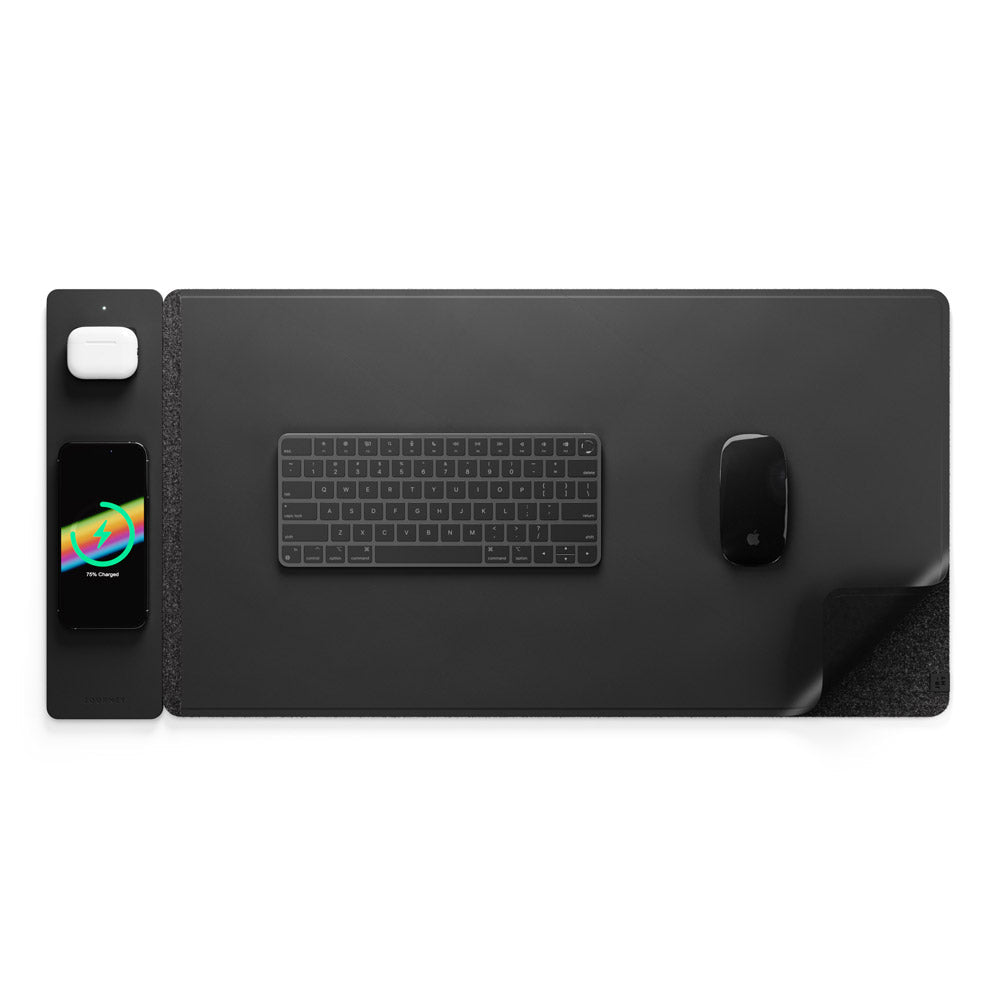 Overhead view of the black wireless charging desk mat set up with a keyboard, mouse, phone, and earbuds.