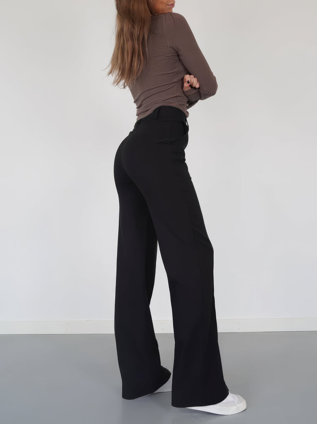 Side view of woman wearing black wide-leg trousers