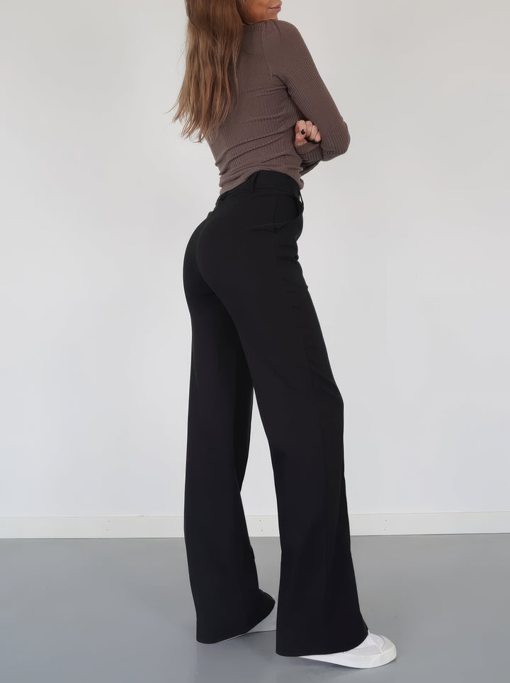 Side view of woman wearing black wide-leg trousers