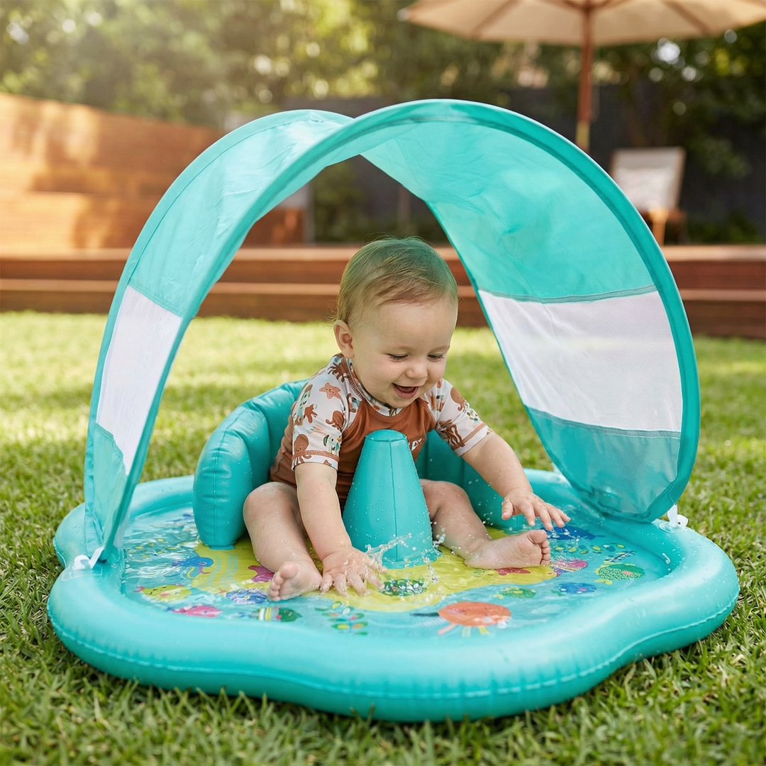 Happy toddler sitting in an inflatable turquoise baby splash play mat with sun canopy on grass